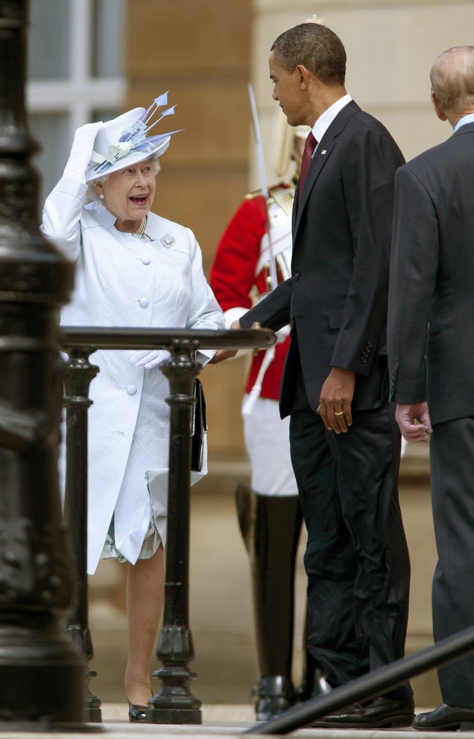 President Obama Standing With Queen Elizabeth II As She Holds Her Hat