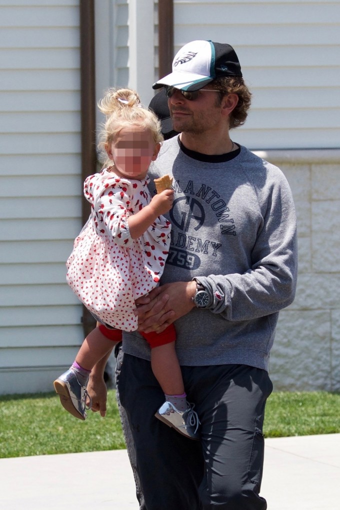 Bradley Cooper Carries His Daughter Lea As She Nibbles
