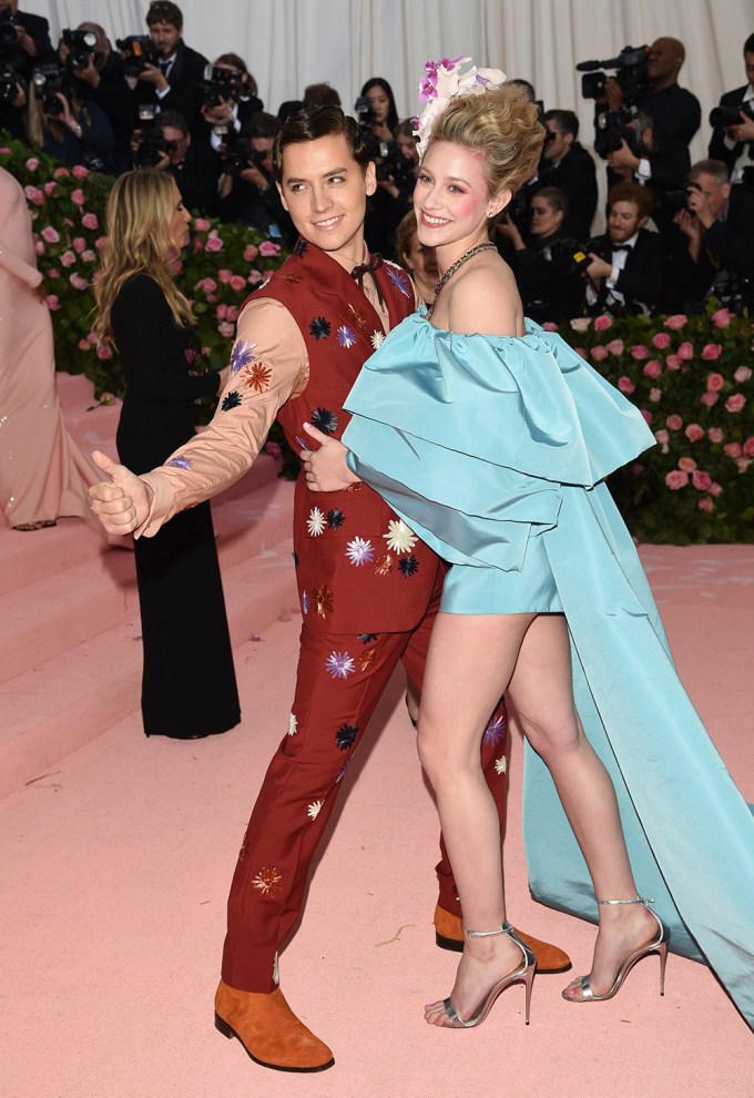 Cole Sprouse and Lili Reinhart smile on the carpet