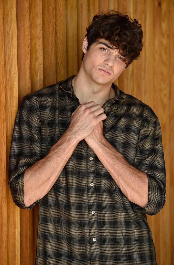 Noah Centineo poses with his hands clasped together