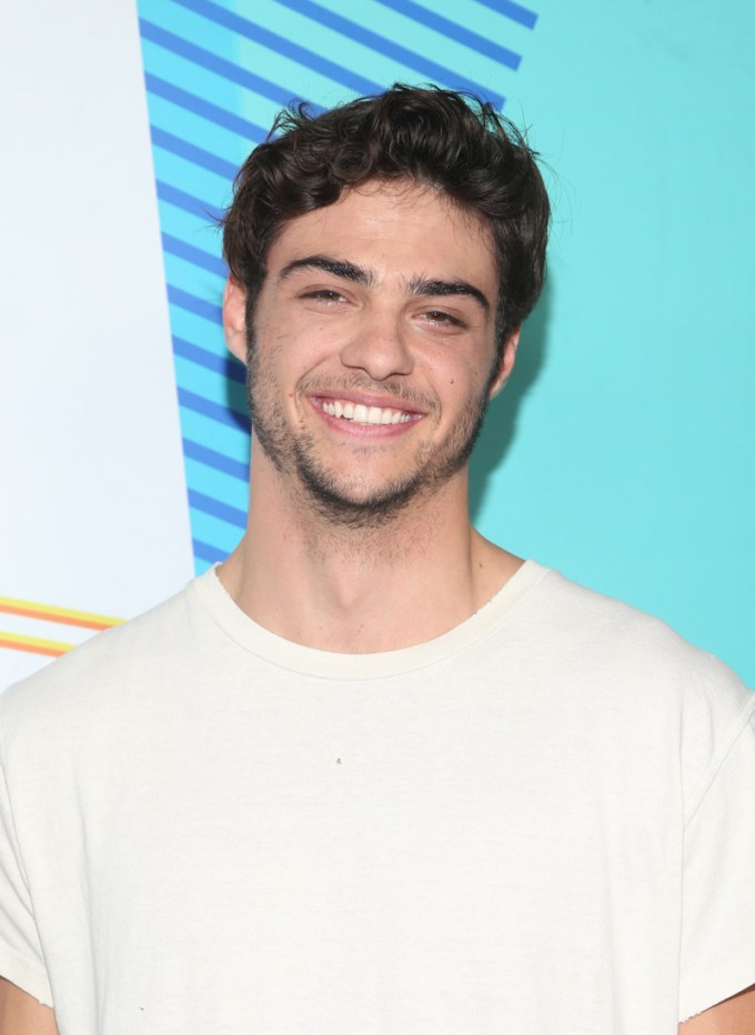 Noah Centineo smiles in a white T-shirt