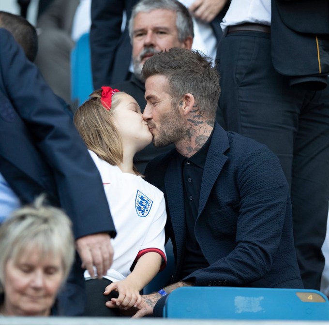 David Beckham gives his daughter Harper a kiss.