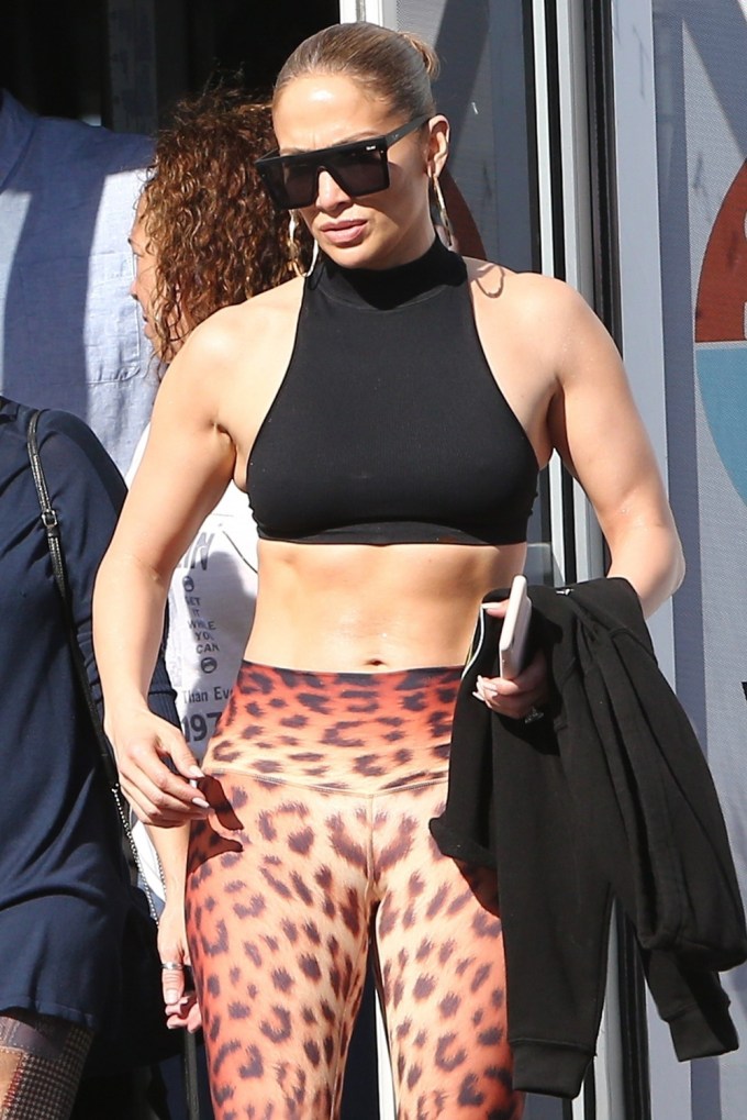 Jennifer lopez seen wearing a black hoodie and black leggings with a pair  of neon green