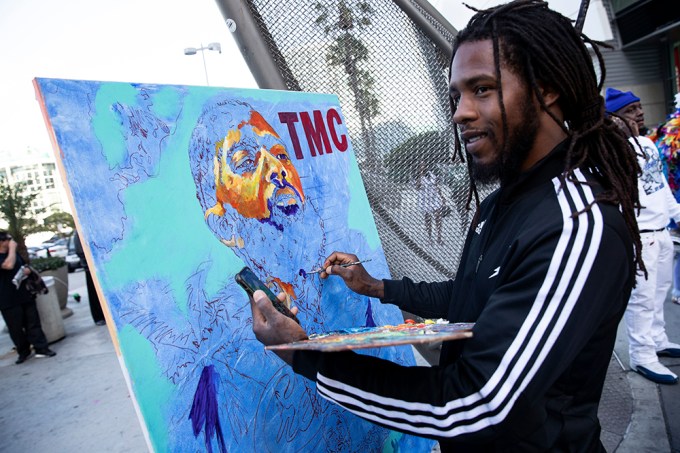 A Nipsey Hussle fan paints a picture of him at his memorial