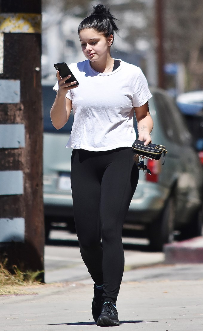 Ariel Winter checks her phone while wearing black leggings
