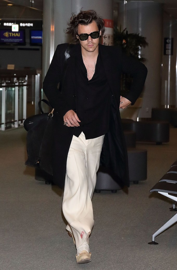 Harry Styles in a black trench in Japan