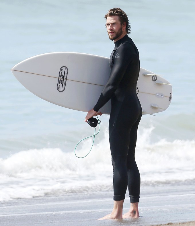 Liam Hemsworth surfing at the beach in Los Angeles