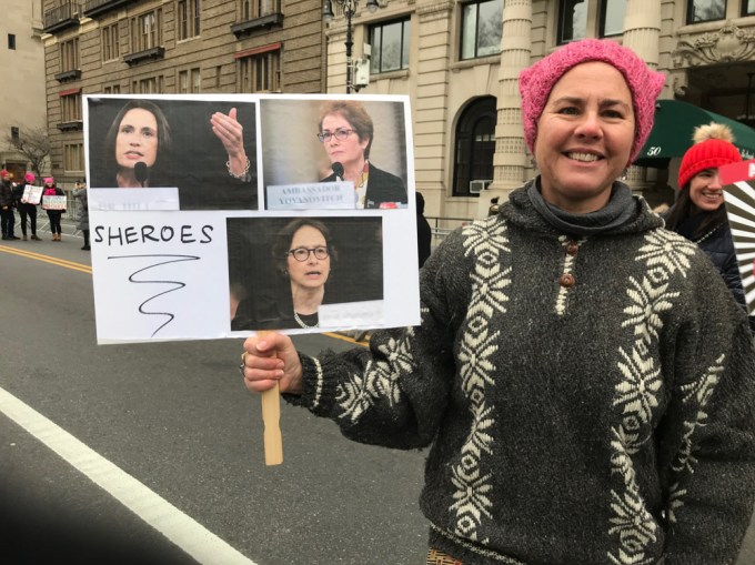 A Woman Holds A Sign Featuring Powerful Female Figers