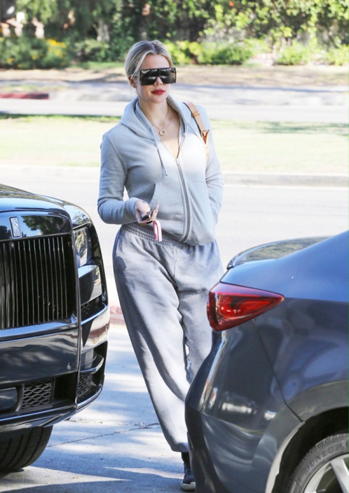 Khloe Kardashian heads to her car in a grey zip-up and sweatpants