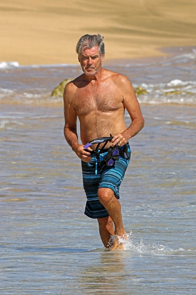 Pierce Brosnan wades through the ocean shirtless