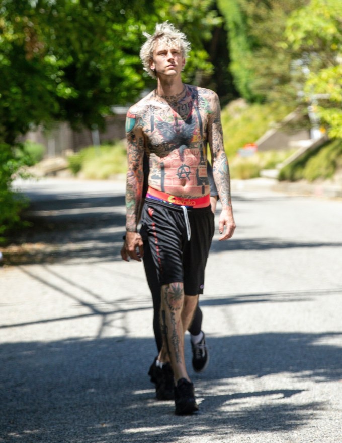 Machine Gun Kelly shows his chest and arms covered in tattoos