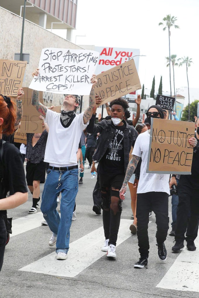 Machine Gun Kelly and Travis Barker holding signs