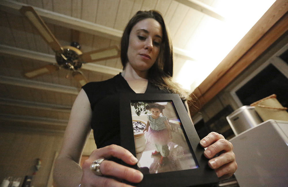 In this Feb. 13, 2017 photo, Casey Anthony poses with a photo of her daughter Caylee during an interview in her West Palm Beach, Fla., home. Anthony, 30, opens up for the first time on-the-record about the death of her daughter in 2008. (AP Photo/Joshua Replogle)