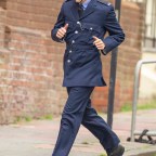 Harry Styles dressed as a  1950's British policeman runs down the street with David Dawson as they film My Policeman in Brighton