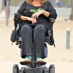 EXCLUSIVE: Dance Moms star Abby Lee Miller doesn’t flinch as a gymnast SOMERSAULTS over her during an outing to an LA beach. The reality TV star, 55, bravely lay back in her wheelchair as the muscular shirtless performer ran towards her then vaulted above her. Miller, who shot to fame as the star of hit show Dance Moms, has been using a wheelchair after undergoing surgery to remove a tumor from her spinal cord after reportedly being diagnosed with a form of cancer called Burkitt Lymphoma. Miller’s visit to the beach in Santa Monica, CA, saw her talking to a man and a woman dressed in workout gear before giving him a series of dance lessons. An onlooker said: “Abby was in great form and started giving the guy dance lessons. "She was teaching him to move and how and when to move his feet and it seemed he was struggling to get the hang of it. It was like she was back on the show Dance Moms and was shouting orders at him to ‘move to the side’ or ‘back right’. She appeared to be trying to teach him ballet just like she did to kids on the series. “It looked the guy had some gymnastic training and so afterwards they did a stunt where he ran at her and somersaulted directly above her.” Miller spent eight seasons on Dance Mom and previously taught Joelle Joanie “Jojo” Siwa. In 2017 she was sentenced to 366 days in prison for bankruptcy fraud. 31 Aug 2021 Pictured: Abbey Lee Miller. Photo credit: KAT/MEGA TheMegaAgency.com +1 888 505 6342 (Mega Agency TagID: MEGA782922_021.jpg) [Photo via Mega Agency]