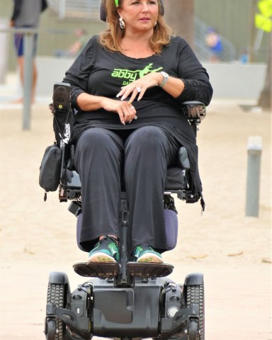 EXCLUSIVE: Dance Moms star Abby Lee Miller doesn’t flinch as a gymnast SOMERSAULTS over her during an outing to an LA beach. The reality TV star, 55, bravely lay back in her wheelchair as the muscular shirtless performer ran towards her then vaulted above her. Miller, who shot to fame as the star of hit show Dance Moms, has been using a wheelchair after undergoing surgery to remove a tumor from her spinal cord after reportedly being diagnosed with a form of cancer called Burkitt Lymphoma. Miller’s visit to the beach in Santa Monica, CA, saw her talking to a man and a woman dressed in workout gear before giving him a series of dance lessons. An onlooker said: “Abby was in great form and started giving the guy dance lessons. "She was teaching him to move and how and when to move his feet and it seemed he was struggling to get the hang of it. It was like she was back on the show Dance Moms and was shouting orders at him to ‘move to the side’ or ‘back right’. She appeared to be trying to teach him ballet just like she did to kids on the series. “It looked the guy had some gymnastic training and so afterwards they did a stunt where he ran at her and somersaulted directly above her.” Miller spent eight seasons on Dance Mom and previously taught Joelle Joanie “Jojo” Siwa. In 2017 she was sentenced to 366 days in prison for bankruptcy fraud. 31 Aug 2021 Pictured: Abbey Lee Miller. Photo credit: KAT/MEGA TheMegaAgency.com +1 888 505 6342 (Mega Agency TagID: MEGA782922_021.jpg) [Photo via Mega Agency]