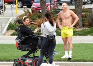 EXCLUSIVE: Dance Moms star Abby Lee Miller doesn’t flinch as a gymnast SOMERSAULTS over her during an outing to an LA beach. The reality TV star, 55, bravely lay back in her wheelchair as the muscular shirtless performer ran towards her then vaulted above her. Miller, who shot to fame as the star of hit show Dance Moms, has been using a wheelchair after undergoing surgery to remove a tumor from her spinal cord after reportedly being diagnosed with a form of cancer called Burkitt Lymphoma. Miller’s visit to the beach in Santa Monica, CA, saw her talking to a man and a woman dressed in workout gear before giving him a series of dance lessons. An onlooker said: “Abby was in great form and started giving the guy dance lessons. "She was teaching him to move and how and when to move his feet and it seemed he was struggling to get the hang of it. It was like she was back on the show Dance Moms and was shouting orders at him to ‘move to the side’ or ‘back right’. She appeared to be trying to teach him ballet just like she did to kids on the series. “It looked the guy had some gymnastic training and so afterwards they did a stunt where he ran at her and somersaulted directly above her.” Miller spent eight seasons on Dance Mom and previously taught Joelle Joanie “Jojo” Siwa. In 2017 she was sentenced to 366 days in prison for bankruptcy fraud. 31 Aug 2021 Pictured: Abbey Lee Miller . Photo credit: KAT/MEGA TheMegaAgency.com +1 888 505 6342 (Mega Agency TagID: MEGA782922_032.jpg) [Photo via Mega Agency]