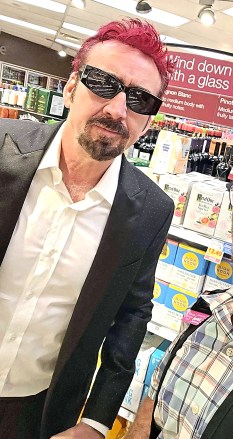 EXCLUSIVE: Nicolas Cage was spotted overdressed grocery shopping Saturday in Las Vegas, wearing a long sleeve white dress shirt with a black coat and sporting his new bright red hair. Hopefully, 
