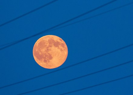 The full moon shines red behind a high tension wire near Jacobsdorf, Germany, 20 June 2016. The arriving night was the shortest of the year. The late setting sun colored the full moon red. The natural phenomenon is called 'strawberry moon.' Photo by: Patrick Pleul/picture-alliance/dpa/AP Images