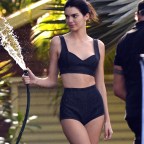 Kendall Jenner wears a black bikini as she plays with a watering hose during a photoshoot in Miami