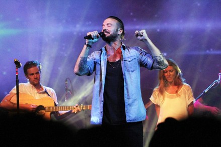 In this July 14, 2013 photo, Pastor Carl Lentz, center, leads a Hillsong NYC Church service at Irving Plaza in New York. With his half-shaved head, jeans and tattoos, Pastor Carl Lentz doesn't look like the typical religious leader. But with its concert-like atmosphere and appeal to a younger demographic, his congregation, Hillsong NYC, is one of the fastest growing evangelical churches in the city. (AP Photo/Tina Fineberg)
