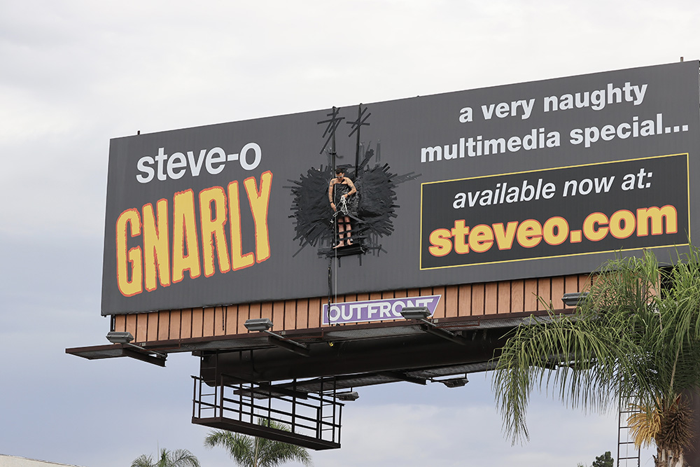 Steve O duct tapes himself to a billboard