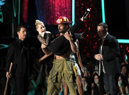 Joe Manganiello holds Elisabeth Banks, center, as she accepts the award for best on screen transformation award during the MTV Movie Awards on Sunday, June 3, 2012, in Los Angeles, as Matthew McConaughey, left, and Channing Tatum, right,  watch. (Photo by Matt Sayles/Invision/AP)