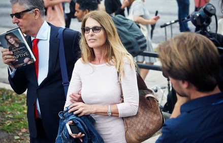 Stanley Zareff, left, holds a book called Captive, authored by actress Catherine Oxenberg, center, as they leave federal court in Brooklyn, Wednesday July 25, 2018, in New York. Oxenberg's daughter India has been named in a criminal complaint against an upstate New York group called NXIVM, accused of branding some of its female followers and forcing them into unwanted sex. (AP Photo/Bebeto Matthews)