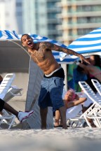 Chris Brown sem camisa brincando com gaivotas na praia em Miami