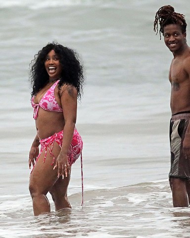 EXCLUSIVE: Singer SZA is all smiles at the beach in Hawaii as she celebrates chart-topping success with her new album 'SOS'. The 33-year-old hitmaker - real name Solana Imani Rowe - looked happy and relaxed as she hit the beach with her producer ThankGod4Cody, who is credited on seven songs on the history-making R&B album. She rocked a plunging pink halter neck swimsuit and matching sarong, also revealing a nip slip as she cooled off with a dip in the ocean. The New Jersey-raised R&B singer-songwriter is currently holding the top spot on the Billboard 200 with her long-awaited second LP. She recently took to Instagram, telling fans: "3 weeks at number one fully minding my business n not giving a f**k . Thank God." In her latest lyrics, the 'Hit Different' songstress has seemingly addressed plastic surgery rumors, responding to rampant speculation around whether her body has been cosmetically enhanced. 03 Jan 2023 Pictured: SZA. Photo credit: MEGA TheMegaAgency.com +1 888 505 6342 (Mega Agency TagID: MEGA929982_021.jpg) [Photo via Mega Agency]