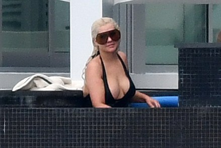 Exclusive: Christina Aguilera wears a black swimsuit and oversized sunglasses as she swims in the pool between recording sessions in Miami. The pop star was also seen playing with her dog and her children and later covered in a white Minnie Mouse robe. February 12, 2021 Photo: Christina Aguilera. Photo provider: MEGA TheMegaAgency.com +1 888 505 6342 (Mega Agency TagID: MEGA733098_001.jpg) [Photo via Mega Agency]