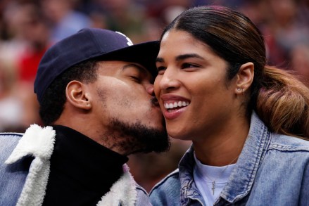 Musician Chance the Rapper, left, kisses his girlfriend Kirsten Corley while attending a preseason NBA basketball game between the Chicago Bulls and the New Orleans Pelicans Sunday, Oct. 8, 2017, in Chicago. (AP Photo/Jim Young)