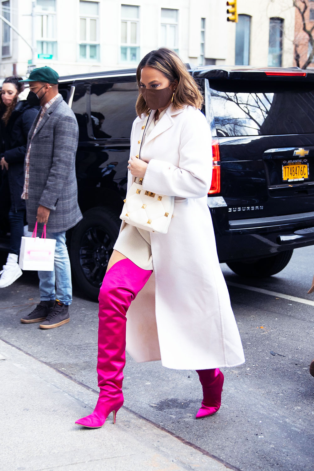 Chrissy Teigen Stuns In A White Coat And Neon Pink Thigh High Boots While Out In NYC