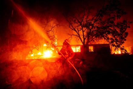 A firefighter sprays water as flames from the Hillside fire consume a residence in San Bernardino, Calif., on . The blaze, which ignited during red flag fire danger warnings, destroyed multiple residences
California Wildfires Blackout, San Bernardino, USA - 31 Oct 2019