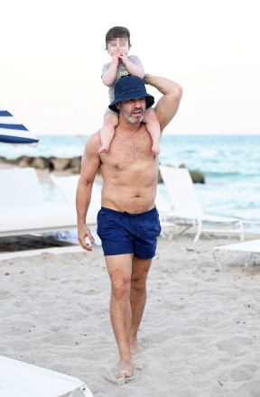 Just before hosting New Year's Eve with Anderson Cooper on CNN, Andy Cohen shows off his toned torso while walking shirtless on the beach in Miami with his 10-month-old son Benjamin on his shoulders.  The creator of the Real Housewives franchise, she is also seen with her trainer.  *SPECIAL INSTRUCTIONS*** Please change the shape of the children's faces before printing.***.  02 Jan 2020 Photo: Andy Cohen;  Benjamin Cohen.  Photo credit: MEGA TheMegaAgency.com +1 888 505 6342 (Mega Agency TagID: MEGA576898_025.jpg) [Photo via Mega Agency]
