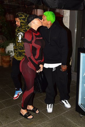 Los Angeles, CA - Amber Rose and Alexander "EA" Edwards kiss for the cameras after dinner with a friend at Avra ​​in Beverly Hills.  The What Happened Last Night actress kept it simple in a black and red outfit.  Her leggings and long sleeve shirt had the same pattern and showed off her toned curves as her baby daddy rocked his signature neon green hair and a black sweatsuit.  Pictured: Amber Rose, Alexander "EA" Edwards BACKGRID USA 19 DECEMBER 2019 USA: +1 310 798 9111 / usasales@backgrid.com UK: +44 208 344 2007 / uksales@backgrid.com *UK Clients - Pictures Containing Children Please Pixelate Face Prior To Publication*