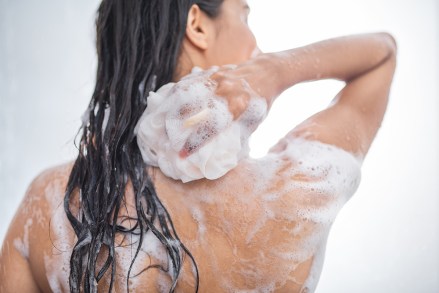 Youth female with wet hair washing body while holding fluffy sponge in hand. Hygiene concept; Shutterstock ID 1134771767; Comments: Art USe