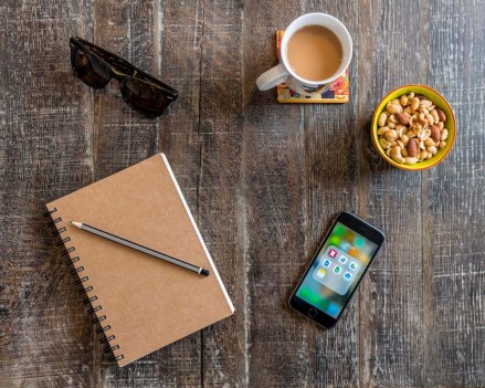 Smartphone, notebook with pen, sunglasses, coffee and nuts, snacks on a wooden table
VARIOUS