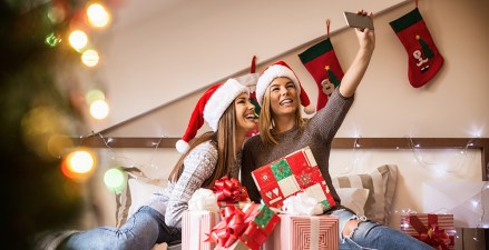 Smiling girlfriends taking a selfie with smarphone. Christmas mood.; Shutterstock ID 516125749; Comments: Art USe