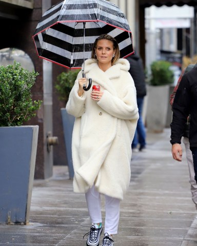 A bundled up Heidi Klum braves the rain with an umbrella and a can of Coke in Los Angeles, California. The newly engaged supermodel was spotted on the set on Germany's Next Topmodel with her sparkler from fianc√© Tom Kaulitz on full display. Wrapped up in an on-trend cream teddy coat, and butterfly earrings, Heidi strolled through Donwtown Los Angeles with a striking striped umbrella and a can of Coca Cola. She had her hair slicked back showing off her beautifully made up face as she made her way to filming the reality show.Coat ‚Äì Max MaraPictured: Heidi KlumRef: SPL5064037 130219 NON-EXCLUSIVEPicture by: SplashNews.comSplash News and PicturesLos Angeles: 310-821-2666New York: 212-619-2666London: +44 (0)20 7644 7656Berlin: +49 175 3764 166photodesk@splashnews.comWorld Rights