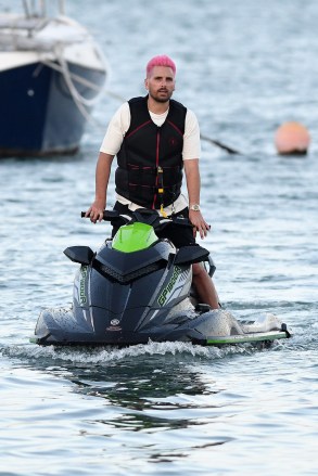 EXCLUSIVE: Scott Disick shows off his new pink hair as he takes a ride on a jet ski while girlfriend Amelia Hamlin waits on the dock with a friend in Miami. 19 Feb 2021 Pictured: Scott Disick; Amelia Hamlin. Photo credit: MEGA TheMegaAgency.com +1 888 505 6342 (Mega Agency TagID: MEGA734510_004.jpg) [Photo via Mega Agency]
