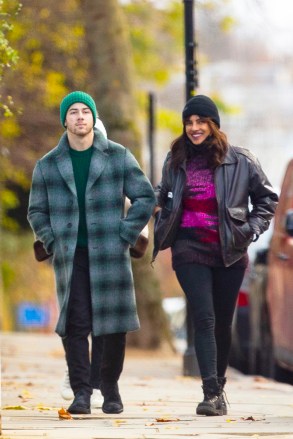 EXCLUSIVE: Nick Jonas and wife Priyanka Chopra Jonas go sightseeing around London ahead of the Christmas holidays. The couple, who have been married for two years, wore face masks and stopped for a hot drink at a cafe. The Bollywood actress who is in town to film 'Text for You', looked positively glowing. The happy couple could be seen stopping for Nick to take some funny photos of Priyanka next to a Highway Maintenance van, presumably to have the words ‘High Maintenance’ behind her. The loved up pair could be seen walking along with Priyanka’s mother in tow, always a couple of yards behind them. Nick, 28, and Priyanka, 38, could be seen wearing Christmas colors, with Nick in a green beanie hat and green accented checked woolen overcoat, while Priyanka opted for a dark brown leather jacket with red and pink knitted top, beanie hat, and jeans. 09 Dec 2020 Pictured: Nick Jonas, Priyanka Chopra Jonas. Photo credit: MEGA TheMegaAgency.com +1 888 505 6342 (Mega Agency TagID: MEGA720310_003.jpg) [Photo via Mega Agency]