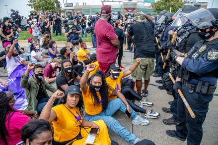 Tiffany Hicks, from left, Yandy Smith and Porsha Williams sit down in front of police during the Good Trouble Tuesday march for Breonna Taylor, on Tuesday, Aug. 25, 2020, in Louisville, Ky. (Amy Harris/Invision/AP)