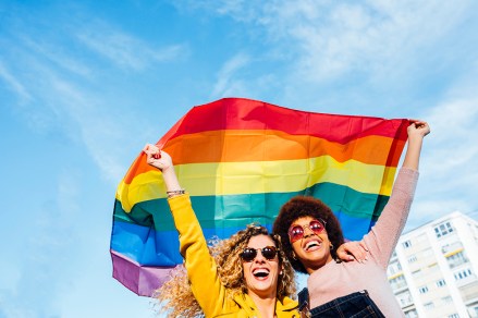 Two women friends hanging out in the city waving LGBT with pride flag; Shutterstock ID 1542337757; Comments: art use