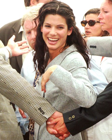 American actress Sandra Bullock is protected by bodyguards after posing for photographers on the beachfront in Cannes, French Riviera, Wednesday May 15, 1996. Bullock and her British director Richard Attenborough are in Cannes to promote their movie "In love and war" during the 49th International Film Festival.(AP PHOTO/Laurent Rebours)
