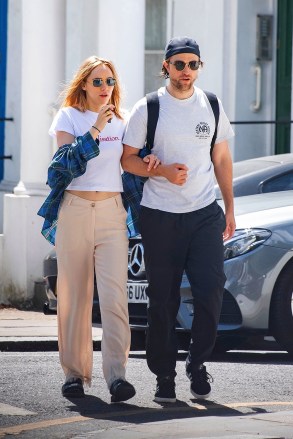 *EXCLUSIVE* London, UK - Braless Suki Waterhouse was spotted smoking an e-cigarette while walking with Robert Pattinson.  The couple were spotted walking in London looking very affectionate as they walked hand in hand.  Suki is wearing a crop top with Realistation print on it and beige flared pants.  While Robert wore his signature cap upside down, a white T-shirt and baggy trousers.  Photo: Suki Waterhouse, Robert Pattinson BACKGRID USA July 21, 2020 US: +1 310 798 9111 / usasales@backgrid.com UK: +44 208 344 2007 / uksales@backgrid.com *UK customers - Images with children Please colorize faces before viewing Publish* *CUSTOMERS LIMITATION APPLICATION*