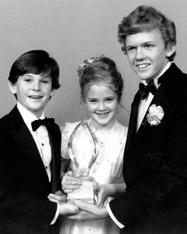Drew Barrymore, center, Henry Thomas, left, and Robert Macnaughton, the young stars of Steven Spielberg's movie "E.T., The Extra-Terrestrial," pose with their People's Choice award after the movie was named favorite Motion Picture at the 9th annual People's Choice Awards in Santa Monica, Ca., on March 17, 1983. (AP Photo/Lennox McLendon)