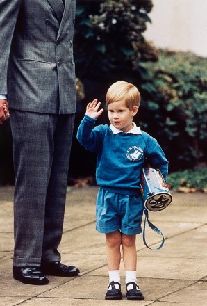 FILE - In this Sept.  16, 1987 file photo, Britain's Prince Harry waves to photographers while holding a 'Thomas The Tank Engine' bag on his first day at a kindergarten in Notting Hill, West London.  Britain's Prince Harry has recorded a special message to celebrate the 75th anniversary of Thomas The Tank Engine, introducing a new program called 'Thomas And Friends: The Royal Engine' that includes the Queen Elizabeth II and his father Prince Charles as animated characters which will be screened in the US on Netflix on May 1, 2020 and in the UK on Channel 5 Milkshake at 9:05am on May 2, 2020. (AP Photo/Martin Cleaver, File)