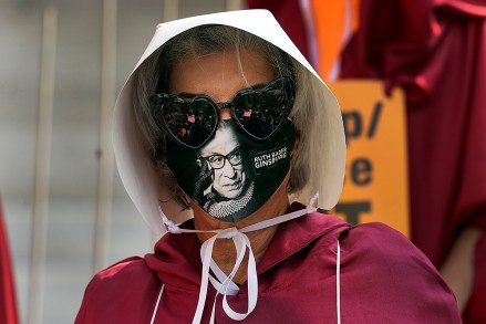 A demonstrator wears a mask with an image of Supreme Court judge Ruth Bader Ginsburg on it during a Women's March Saturday, Oct. 17, 2020, in Los Angeles. Thousands of women rallied in U.S. cities, to oppose President Donald Trump and his fellow Republican candidates in the Nov. 3 elections. (AP Photo/Marcio Jose Sanchez)