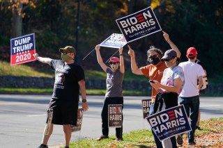 Supporters of President-elect Joe Biden wave signs at the entrance to Trump National golf club in Sterling, Va., Saturday Nov 7, 2020. Trump was at the facility. (AP Photo/Steve Helber)
